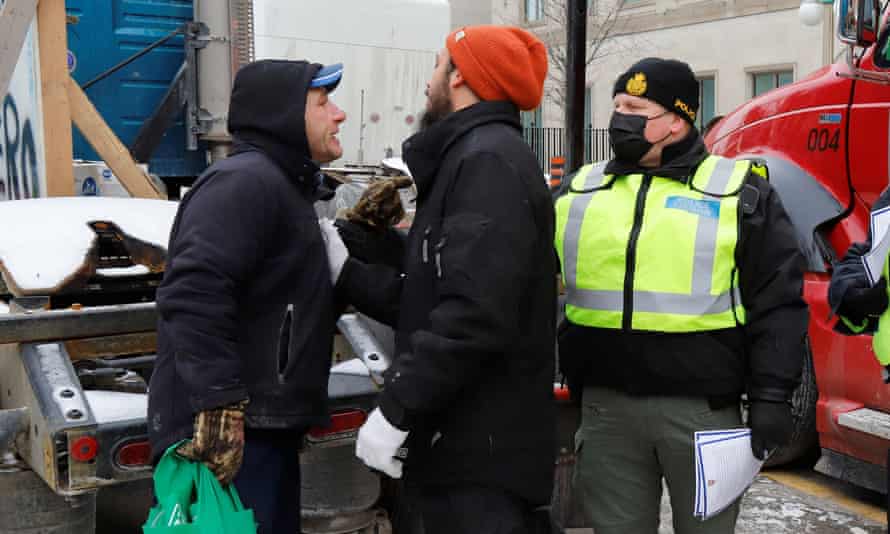 A person confronts a police officer who is handing out a notice telling demonstrators to leave the area, as truckers and their supporters continue to protest against coronavirus vaccine mandates in Ottawa, Canada.