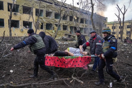 Ukrainian emergency employees and volunteers carry an injured pregnant woman, Irina Kalinina, from a maternity hospital that was damaged by shelling in Mariupol, 9 March. The woman and her baby did not survive.