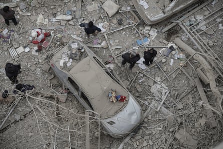 Aerial shot of a car covered in dust and earth from explosiong, debris all around