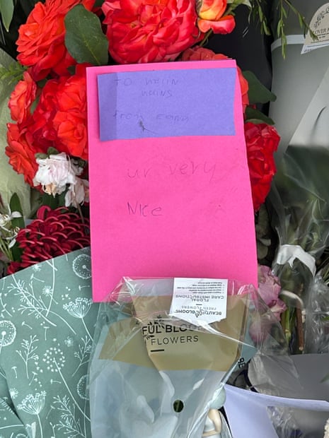 A pink and purple card in front of red flowers outside Helen Haines' electoral office