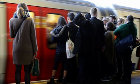Commuters wait on the platform as a tube arrives on the London Underground, November 2016