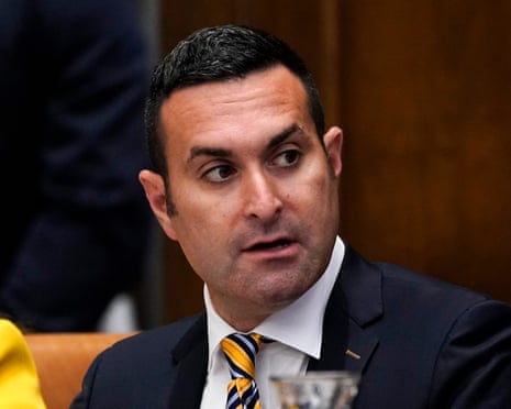 A man in a suit at a table speaks.
