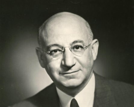A bald, bespectacled man looks at the camera