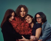 The four members of the Big Moon standing in a close huddle, with frontperson Juliette Jackson wearing voluminous red frills