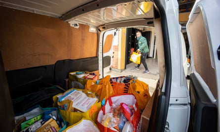 Volunteers from the food bank fill a van with food parcels.