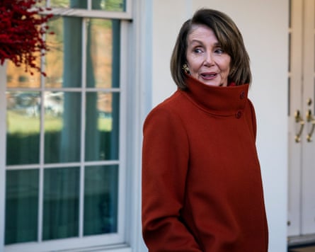 Nancy Pelosi in a red coat with collar pulled up