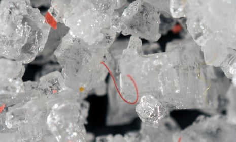 Tiny fragments and filaments of plastic inside and among table salt crystals.