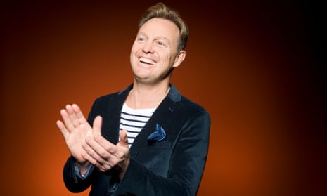 Jason Donovan in a velvet jacket clapping and broadly smiling