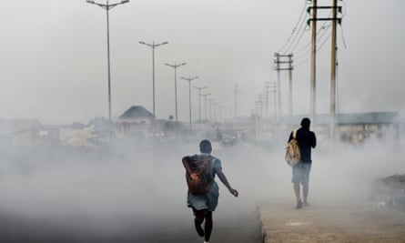 A schoolgirl walks past smoke emitted from a dump in the city of Port Harcourt, Nigeria.