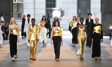 12 models for Gabriela Hearst's New York fashion week collection, some with outfits featuring gold-looking material, walk towards the camera