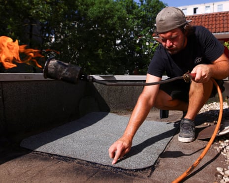 Roofer Jan Tomsen repairs a flat roof, amid a heatwave in Cologne, Germany.