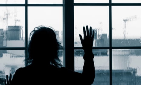 Woman looking out of window on rainy day in silhouette