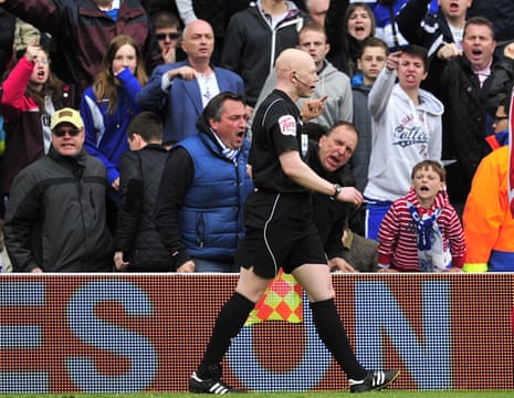 An assistant referee receives abuse from fans.