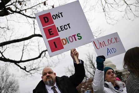 people hold signs that read ‘don’t elect idiots’ and ‘unlock aid’