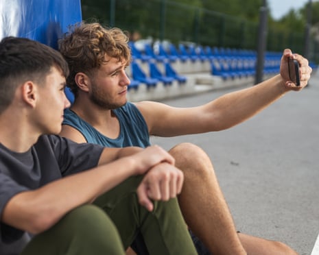 Two young men taking a smartphone self portrait together on a sports court