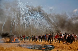 Teargas canisters fired by Israeli security forces explode above Palestinian demonstrators as they run for cover