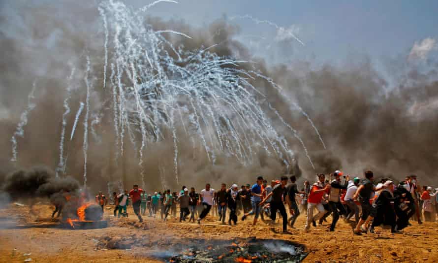 Palestinians run for cover from tear gas during clashes with Israeli security forces.
