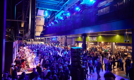 indoor view of people queuing at a bar and waiting to go into the venue, lit in blue and purple