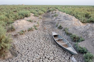 A rowing boat sits in a dried up creek with scrubland on either side