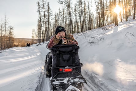 Radik, 10, eats pork rillettes on the back of a snowmobile