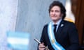 A man wearing a blue suit and a sash with Argentina's flag smiles
