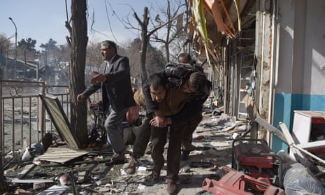 Volunteer rescue workers carry a man away from the scene of a bombing in Kabul, Afghanistan