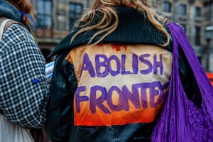 A woman wears a jacket with a message on the back against the EU border agency, Frontex, during a protest in Amsterdam.