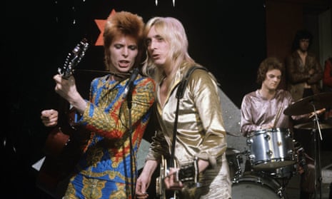 David Bowie, Mick Ronson and Mick ‘Woody’ Woodmansey performing on stage.