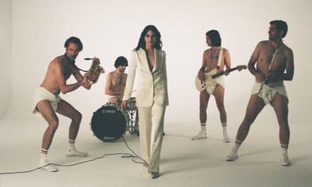 Manfredi in white suit with band of four men in loincloths