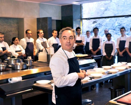 Ferran Adrià in a kitchen with a row of chefs watching him