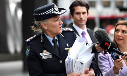 Katarina Carroll is walking outside wearing formal police uniform. She is carrying folders and there are two journalists next to her with microphones