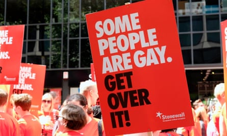 People marching in the sun with the poster 'Some people are gay. Get over it!' on a stick