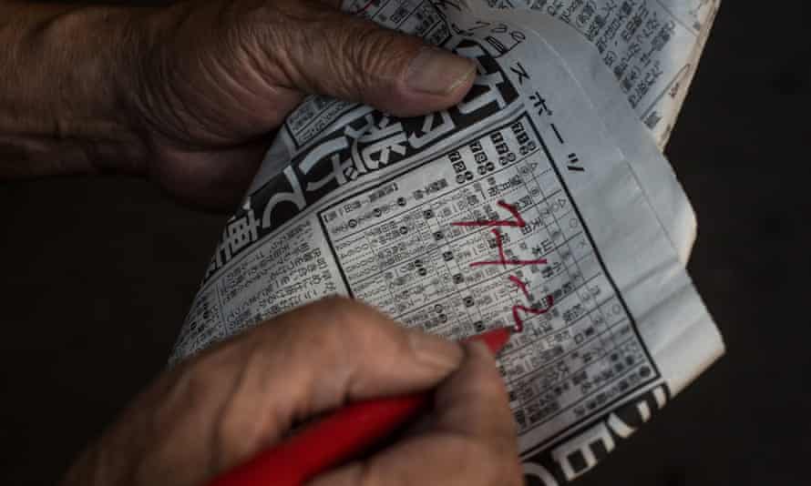 A bettor writes his picks on a form guide at Kawasaki keirin races