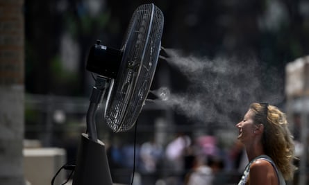 A woman cools down by a fan in Rome.