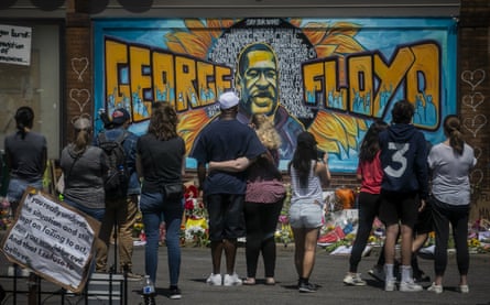 Visitors at a makeshift memorial featuring a mural of George Floyd