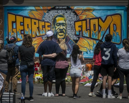 People looking at a street art memorial with a picture of George Floyd