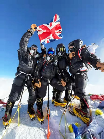 Four British climbers pose on the summit of Everest wearing breathing apparatus and holding up a flag