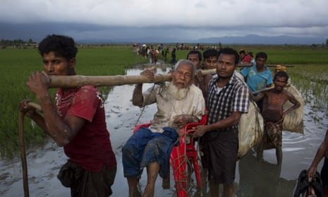Rohingya refugees carry an elderly man as they cross the border into Bangladesh.