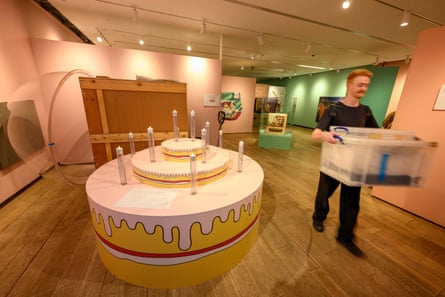Large model of cake with person carrying a box walking by