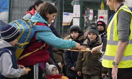 A volunteer offers doughnuts to Ukrainian refugees before their departure from the border crossing in Medyka, south-eastern Poland