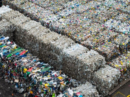 Large cubes made up of milk cartons and other plastic packaging are lined up at a recycling plant.