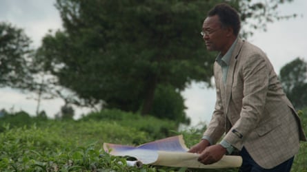 Mungai is standing on a tea plantation, holding a map