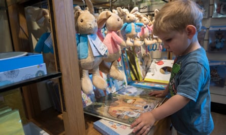 Young boy looks at Peter Rabbit books for sale in the Hill Top gift shop, in the Lake District.