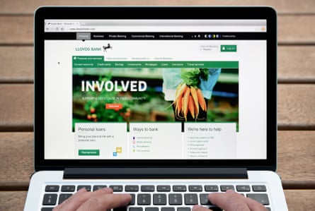 The Lloyds Bank website on MacBook against a wooden bench outdoor background