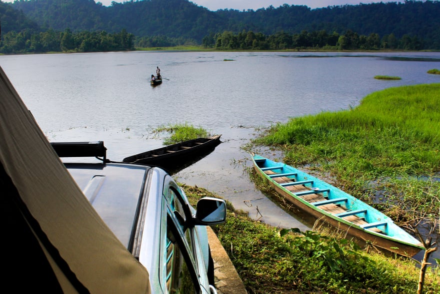 A van parked by a remote lake with a canoe on the shore