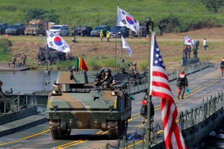 Military vehicle on road with US and South Korean flags visible