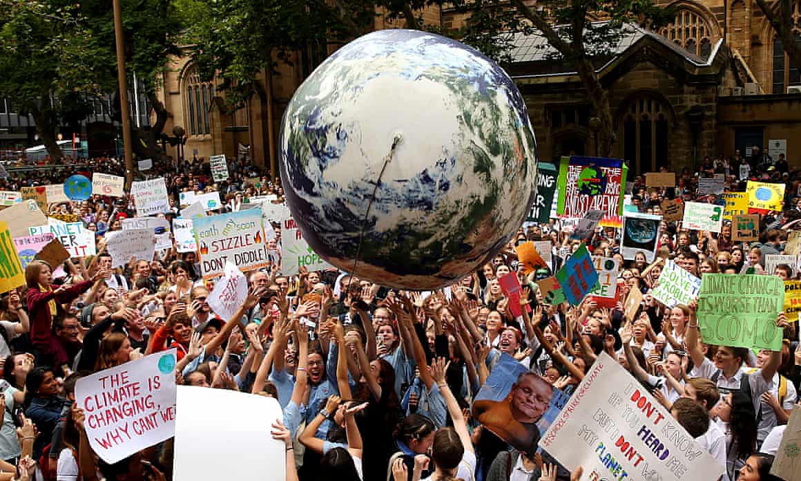 Climate protesters with signs surrounding a model of a globe