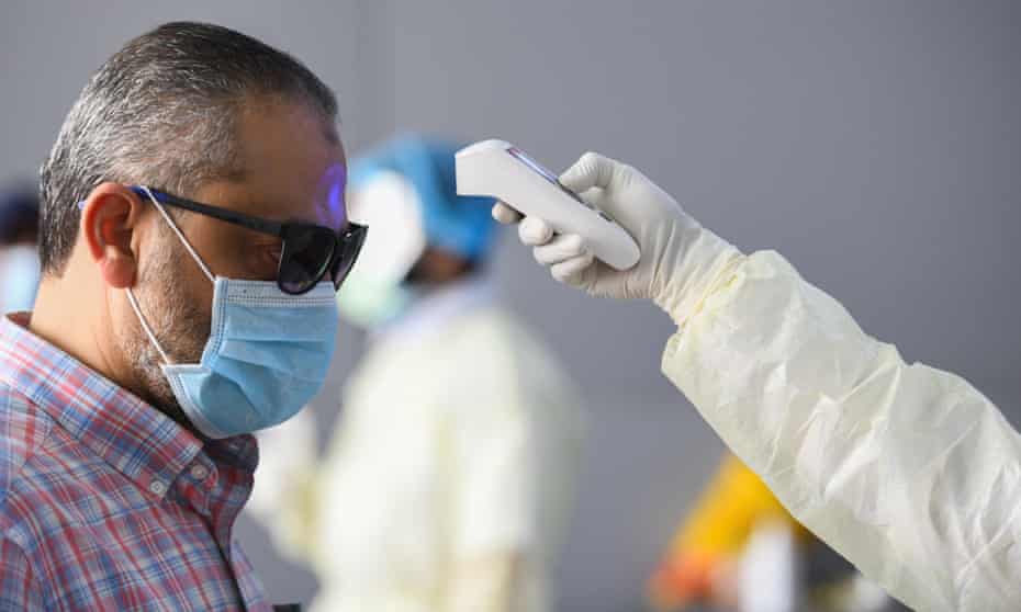A health official checking the body temperature of a man in Kuwait City on 12 March 2020, the day after the WHO declared the coronavirus pandemic.