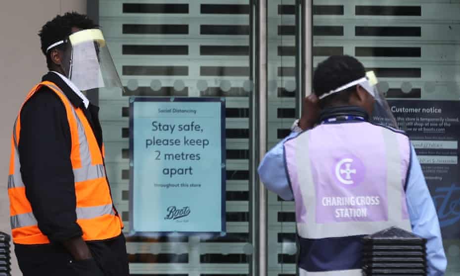 Members of railway staff wearing face shields stand in front of Charing Cross station in London