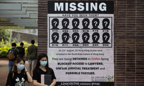 Students at the University of Hong Kong walk past a poster supporting 12 Hongkongers detained in China.
